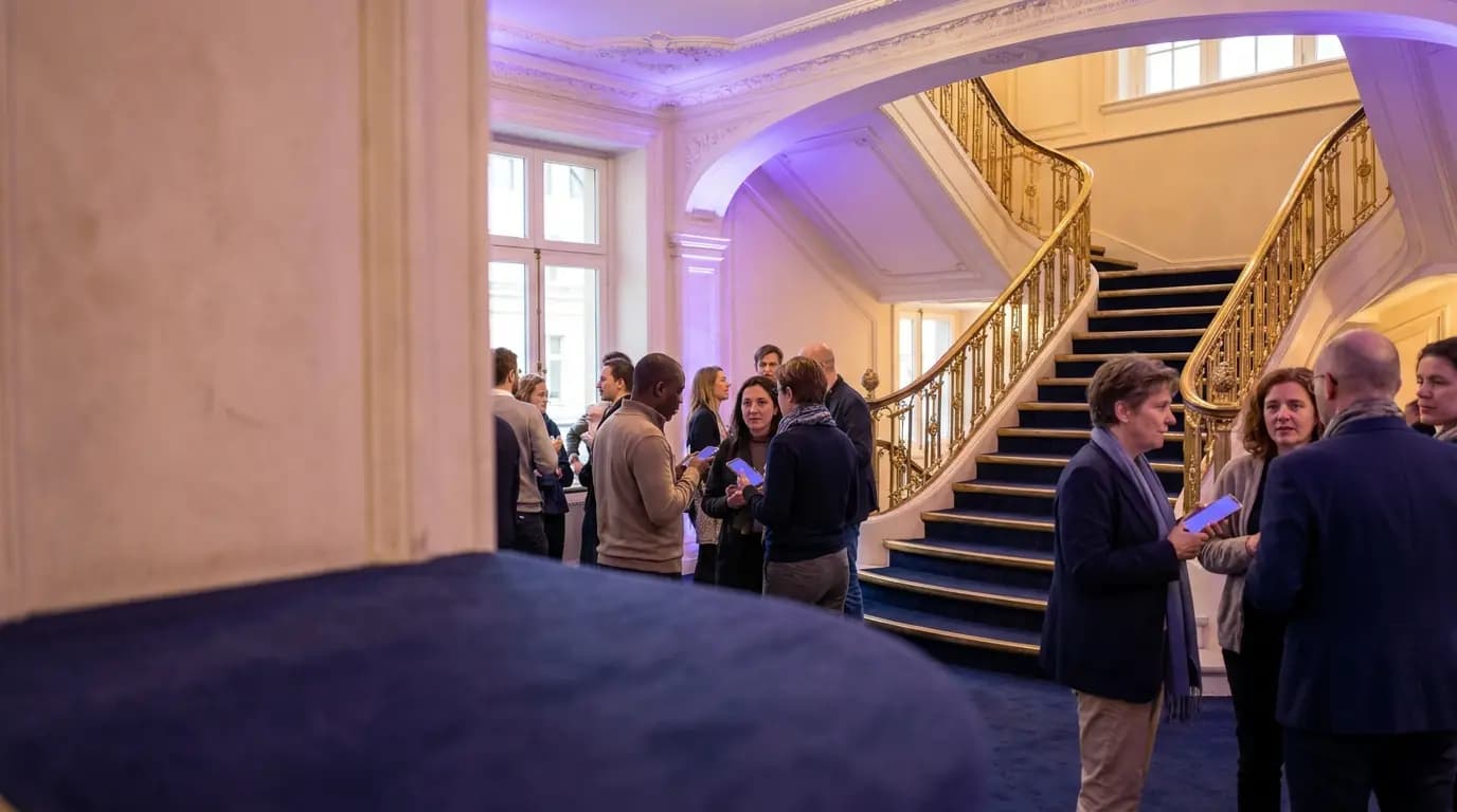 Audience members chatting in a busy theatre foyer before a performance, some holding phones